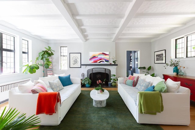 living area featuring radiator, plenty of natural light, beam ceiling, a fireplace, and coffered ceiling