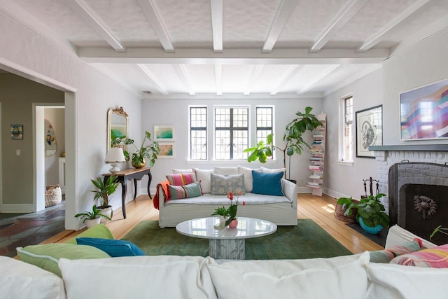 living area featuring healthy amount of natural light, a brick fireplace, beamed ceiling, baseboards, and hardwood / wood-style floors