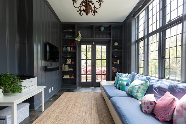 living area with french doors, a chandelier, and stone finish flooring