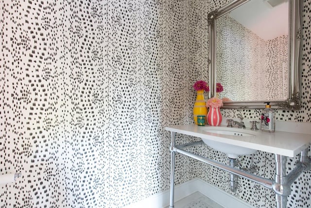 bathroom featuring a sink and wallpapered walls