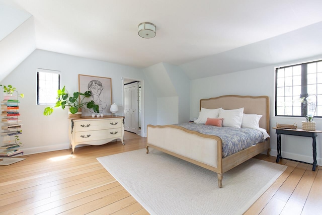 bedroom with light wood finished floors, vaulted ceiling, and baseboards