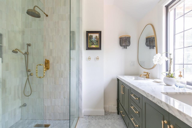 full bathroom featuring tiled shower, double vanity, and baseboards
