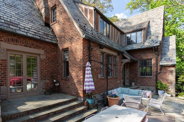 back of property featuring a high end roof, french doors, a patio area, and outdoor lounge area
