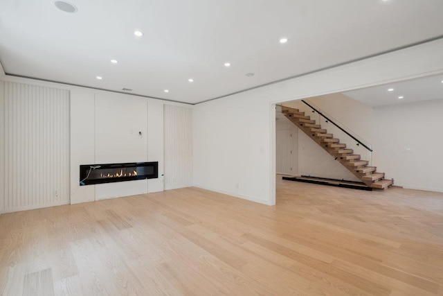 1 Bentley Rd, Great Neck, NY 11023 - unfurnished living room featuring wood finished floors, stairway, a glass covered fireplace, recessed lighting, and baseboards