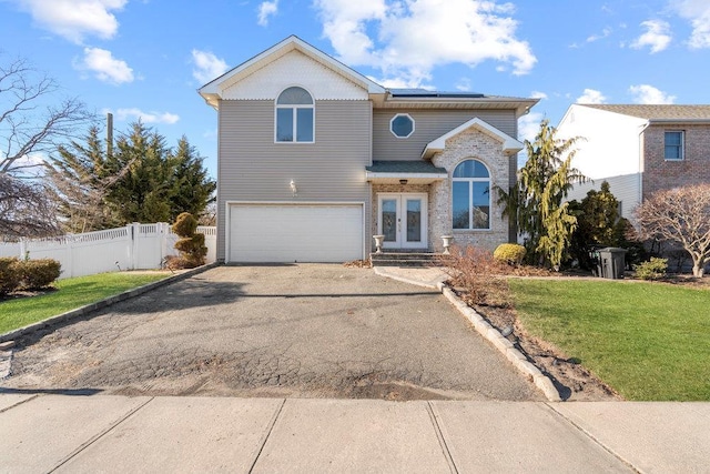 view of front of property with french doors, driveway, roof mounted solar panels, a garage, and brick siding