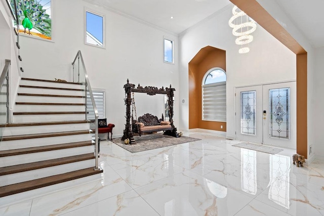 foyer with marble tiled floors, a high ceiling, stairway, a chandelier, and baseboards