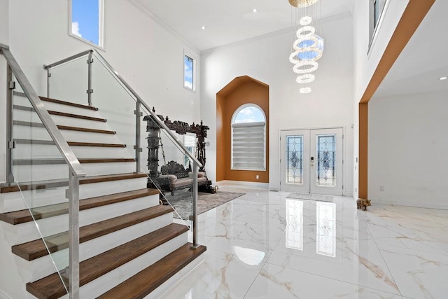 foyer with marble tiled flooring, a towering ceiling, stairway, french doors, and a chandelier