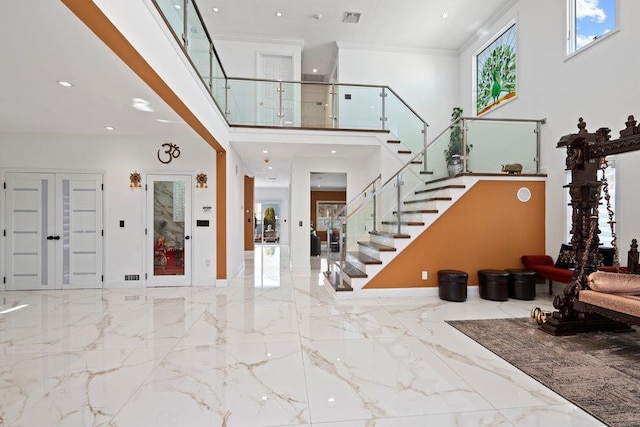 foyer featuring stairs, marble tiled flooring, a towering ceiling, ornamental molding, and baseboards