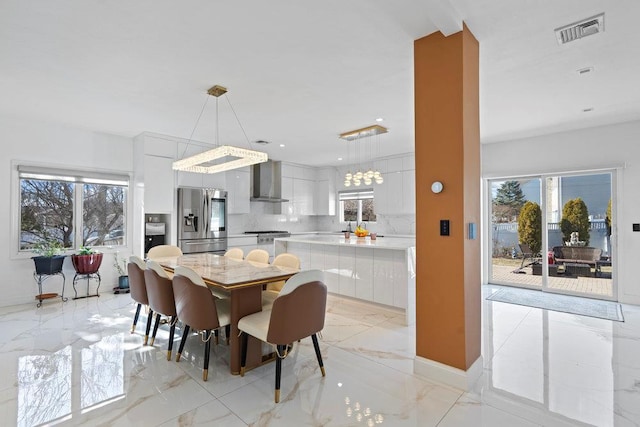 dining room with light marble finish flooring, healthy amount of natural light, and recessed lighting