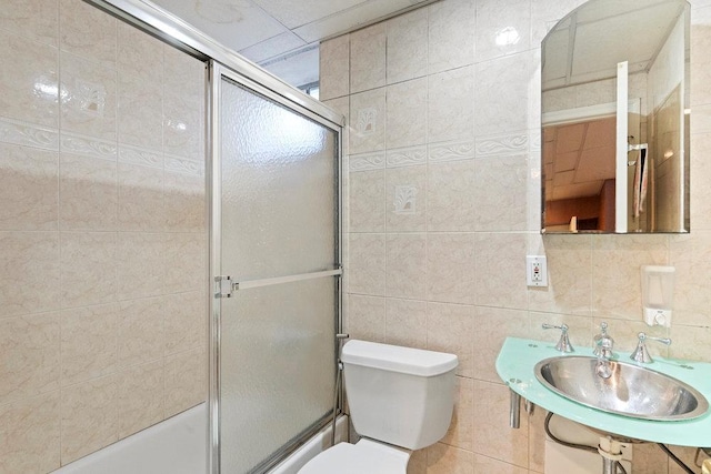 bathroom featuring a sink, tile walls, and toilet