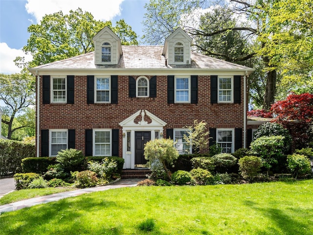 colonial home with a front lawn and brick siding
