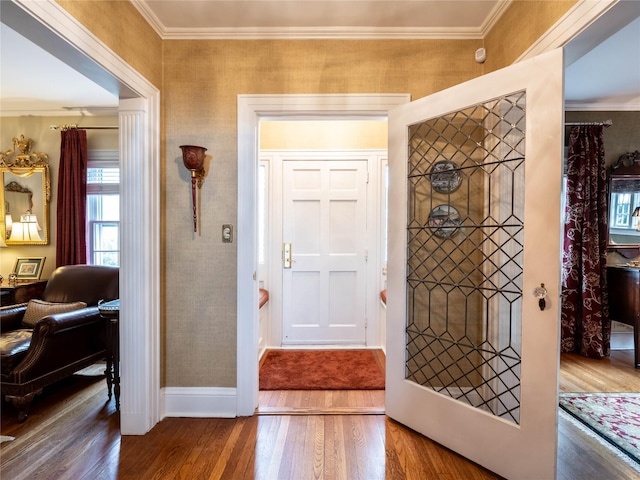foyer with wood finished floors, ornamental molding, and baseboards