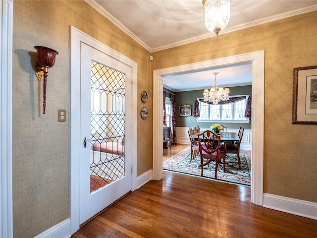 foyer entrance with a chandelier, wood finished floors, ornamental molding, and baseboards