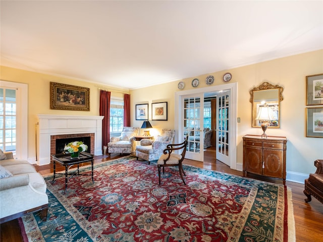 living area featuring wood finished floors, ornamental molding, a fireplace, and baseboards