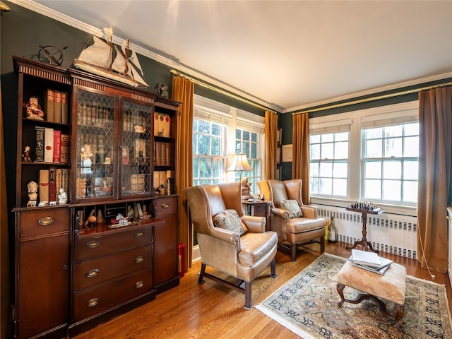 sitting room featuring radiator, ornamental molding, and wood finished floors