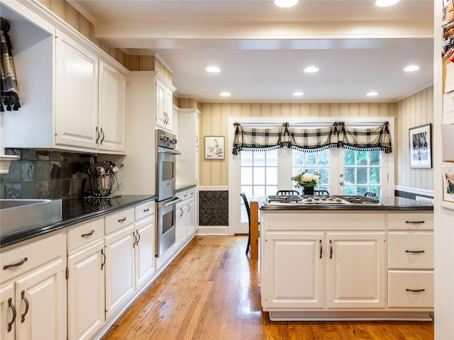 kitchen featuring dark countertops, white cabinetry, appliances with stainless steel finishes, light wood-style flooring, and recessed lighting