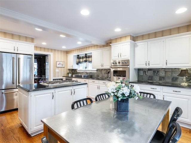 kitchen with stainless steel countertops, stainless steel appliances, a center island, a sink, and tasteful backsplash