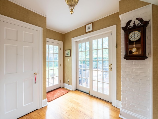 entryway with light wood finished floors, baseboards, and ornamental molding