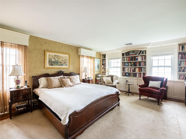 bedroom with light colored carpet, ornamental molding, and multiple windows
