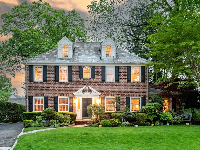 colonial inspired home featuring a front yard, brick siding, and a high end roof