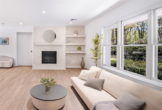 4 Pine Tree Ct, East Quogue, NY 11942 - living area featuring healthy amount of natural light, wood finished floors, a large fireplace, built in shelves, and recessed lighting
