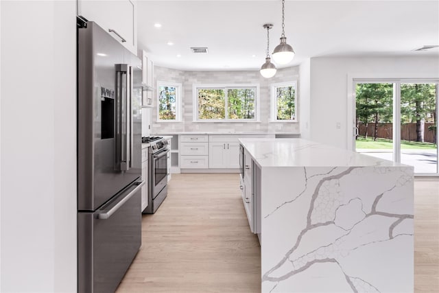 4 Pine Tree Ct, East Quogue, NY 11942 - kitchen with appliances with stainless steel finishes, a center island, light wood-style flooring, white cabinetry, and hanging light fixtures