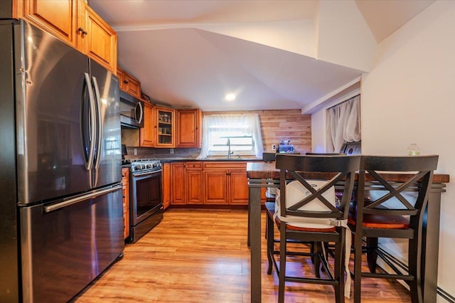 133B Edgewater Park Unit 133B, Bronx, NY 10465 - kitchen featuring stainless steel appliances, brown cabinets, light wood-style floors, dark countertops, and lofted ceiling