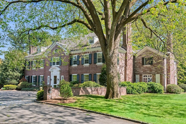 georgian-style home featuring brick siding and a front yard