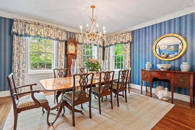 dining room featuring a chandelier, wallpapered walls, wood finished floors, ornamental molding, and healthy amount of natural light
