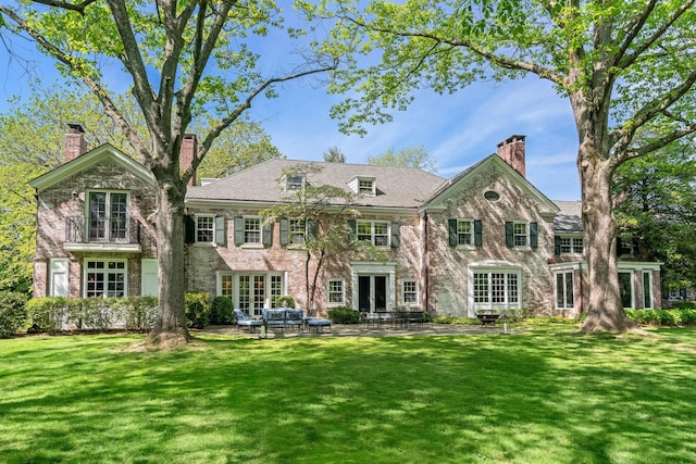 rear view of property with a chimney, a lawn, a patio area, and french doors