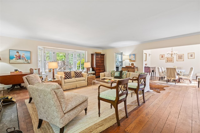 living room with crown molding, a chandelier, and light wood-type flooring