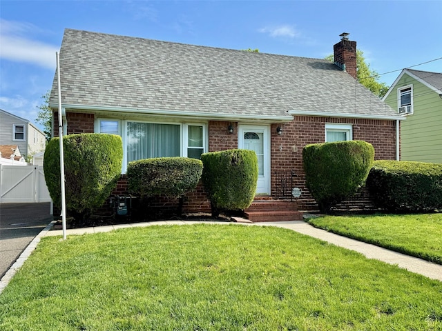 cape cod-style house with a shingled roof, brick siding, a chimney, and a gate
