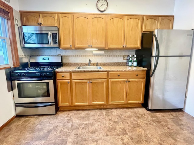 kitchen with appliances with stainless steel finishes, a sink, and light countertops