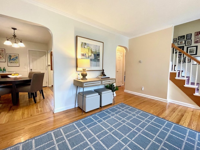 foyer entrance with arched walkways, wood finished floors, baseboards, crown molding, and a chandelier