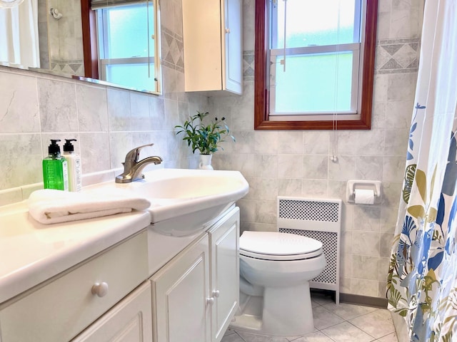 full bathroom with radiator, tile patterned floors, toilet, vanity, and tile walls