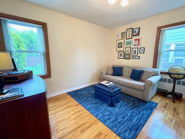 living room featuring light wood-type flooring, radiator, and baseboards