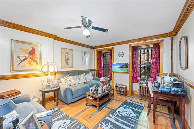 living room featuring crown molding, wood-type flooring, ceiling fan, and a wainscoted wall