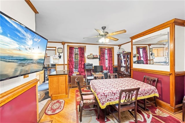 dining room featuring crown molding, a ceiling fan, light wood-style flooring, and radiator heating unit