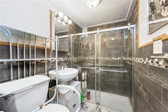 bathroom with a shower stall, ornamental molding, tile walls, toilet, and a sink