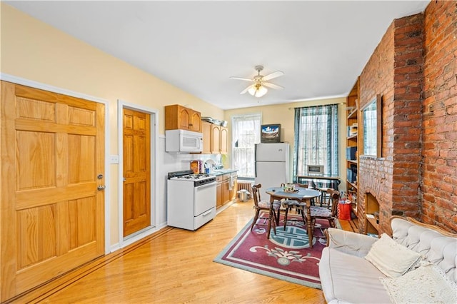 kitchen with white appliances, light wood finished floors, ceiling fan, and brick wall