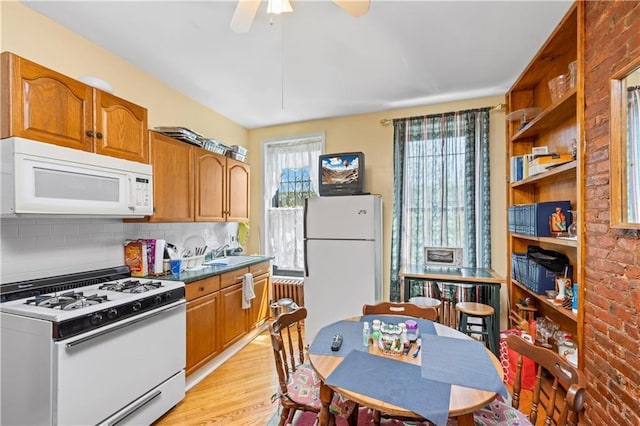 kitchen featuring white appliances, a sink, light wood-style flooring, decorative backsplash, and ceiling fan
