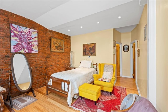 bedroom featuring wood finished floors, brick wall, vaulted ceiling, and recessed lighting