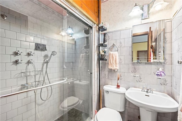 full bath with tile walls, a stall shower, toilet, and a sink