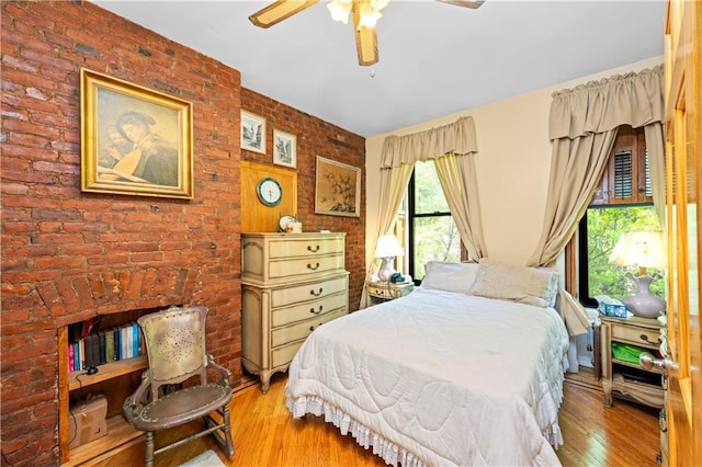 bedroom featuring wood finished floors, brick wall, and ceiling fan