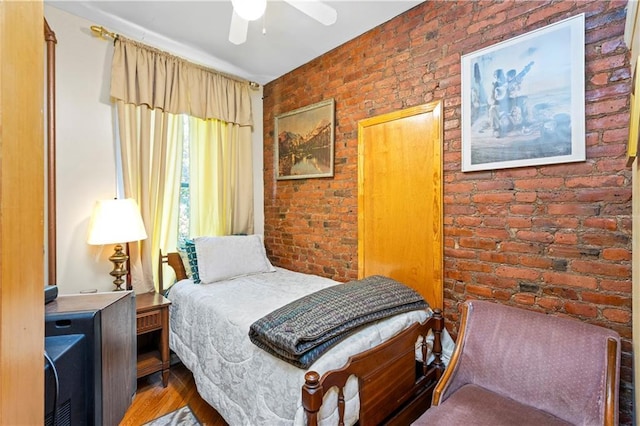 bedroom with brick wall, wood finished floors, and ceiling fan
