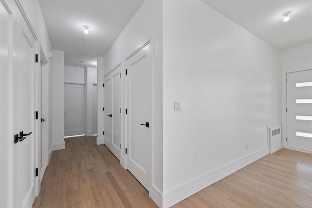 corridor featuring light wood-type flooring and baseboards