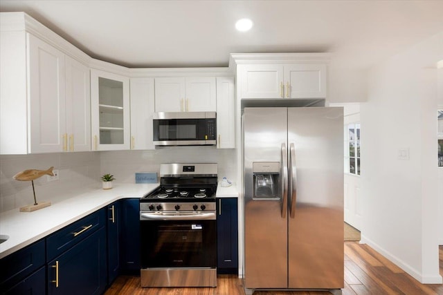 886 S 8th St, Lindenhurst, NY 11757 - kitchen with stainless steel appliances, blue cabinetry, white cabinets, wood finished floors, and light countertops
