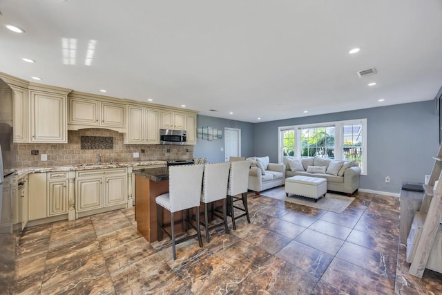 59 Saddle Ln, Levittown, NY 11756 - kitchen featuring cream cabinetry, stainless steel microwave, a sink, light stone counters, and recessed lighting