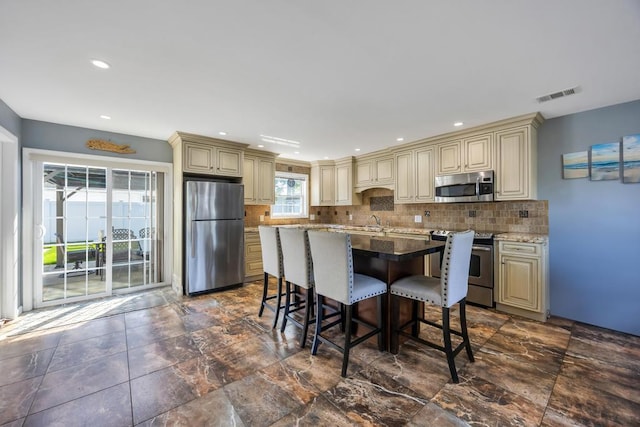 59 Saddle Ln, Levittown, NY 11756 - kitchen with cream cabinetry, appliances with stainless steel finishes, an island with sink, backsplash, and recessed lighting