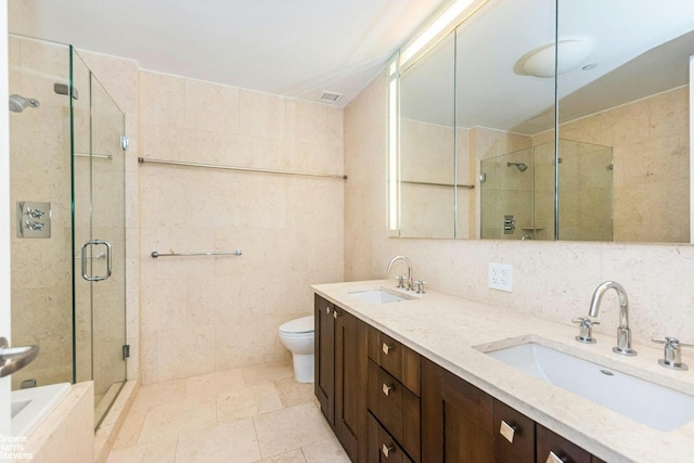 full bath with tile walls, a stall shower, toilet, double vanity, and decorative backsplash